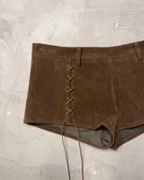 Shorts de gamuza color marrón oscuro, de tiro alto, con cordones cruzados a los costados a modo de ajuste o decoración.
