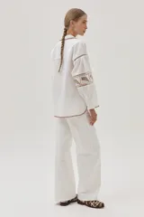 Camisa blanca de mangas largas abullonadas con bordados combinados y guardas, además de delicados bordados en el cuello y el bajo.