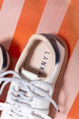 Championes de cuero blancos con suela de goma color caramelo y cordones moteados en blanco y negro.