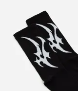 Medias de caña larga color negro con estampado abstracto en blanco en el lateral. Confeccionadas en algodón, poliamida y otras fibras.