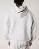 Hoodie gris melange de corte oversize, con cuello alto y mangas globo con puños ajustados. Presenta un bolsillo canguro frontal y un pequeño logo bordado sutil en el pecho.