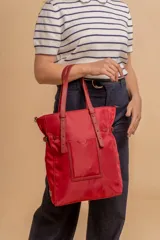 Cartera tipo tote bag color negro, con doble asa de mano y correa bandolera ajustable. Presenta un bolsillo rectangular en el frente.