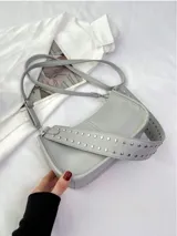 Bolso bandolera negro de cuero sintético con tachas plateadas en las correas.