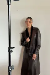 Trench de cuero ovino color chocolate con detalles en pasamanería de cueros en tonos tierra. Tiene lazos en mangas y espalda para entallar.