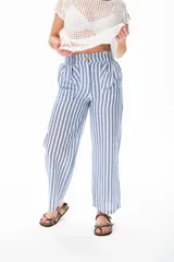 Pantalón largo a rayas verticales azules y blancas, con botón de coco, cintura elastizada y plizado en el bolsillo.