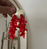 Par de aros colgantes rojos hechos a mano en porcelana con forma de brotes irregulares. Cada pieza es única.
