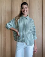 Camisa verde con rayas verticales blancas, de corte holgado, manga 3/4 y dos bolsillos frontales.