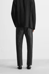 Pantalón de jean negro con efecto lavado, corte slim fit, cinco bolsillos y cierre frontal con botones.