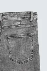 Pantalón de jean negro ajustado al cuerpo desde la cintura hasta el tobillo, de tiro medio y tejido elástico. Diseño de cinco bolsillos con lavado efecto roto y cierre frontal con cremallera y botón.