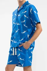 Camisa azul con estampado de sirenas blancas, de corte recto, manga corta y cuello camisero.