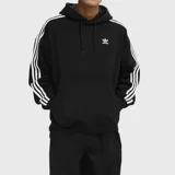 Canguro Adidas Originals negro con capucha, logo bordado en el pecho, bolsillo frontal tipo canguro y tres rayas blancas en las mangas.