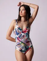 Malla enteriza estampada con motivos florales y hojas en tonos azules, rojos, amarillos y verdes. Escote en V cruzado y breteles regulables.