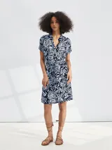 Vestido corto con estampado floral en tonos azul y blanco, con cuello en V, mangas cortas y lazo en la cintura.