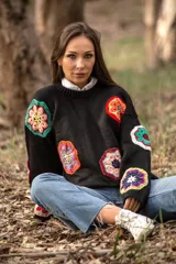 Sweater negro de lana con cuello redondo y apliques de flores de crochet multicolores.