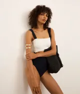 Malla enteriza bicolor, blanca en la parte superior y negra en la parte inferior, confeccionada en microfibra acanalada. Presenta breteles anchos, escote recto, copas removibles y recorte cut-out en el abdomen.