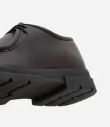 Zapato de vestir negro con cordones, fabricado en cuero sintético, con puntera redondeada y suela de goma.