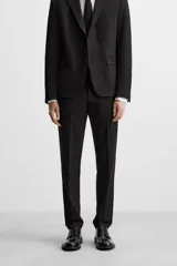 Pantalón de vestir negro slim fit, confeccionado en tejido con viscosa. Cuenta con bolsillos frontales y traseros de vivo. El cierre es frontal con cremallera y botón.