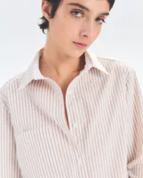 Camisa de algodón de corte holgado con rayas en tonos beige y blanco, y cuello clásico.