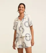 Conjunto de pijama corto blanco con estampado de soles azules. Incluye camisa de manga corta con cuello y short con cintura elástica.