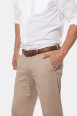 Pantalón de vestir color beige, de corte recto, con bolsillos laterales y traseros. Se ajusta a la cintura con cinturón de cuero marrón.