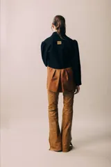 Blazer negro con solapas y cierre con botón de madera. Presenta corte a la cintura y parte inferior color marrón.