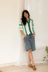 Camisa tejida de algodón a rayas verticales blancas y verdes, con cuello polo, mangas cortas y botones de madera.