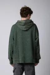 Buzo canguro verde con efecto desgastado, capucha con cordón ajustable, bolsillo frontal y puños con orificio para el pulgar.