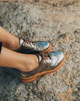 Zapato acordonado color bronce de cuero vacuno con perforaciones decorativas, taco de madera con folia en cuero de 4cm y entre suela de goma de 1,5cm. Horma de punta redonda y cómoda.