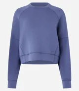 Buzo deportivo femenino confeccionado en microfibra color azul, con cuello redondo, mangas raglán largas y recortes.