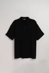 Camisa negra fluida de manga corta con cuello clásico y cierre frontal con botones.