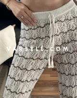 Pantalón de hilo color marrón con rayas horizontales blancas, corte holgado y cintura con cordón ajustable.