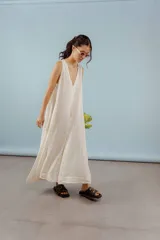 Vestido largo confeccionado en lino de color beige, con escote en V, diseño sin mangas y silueta holgada de caída fluida.