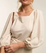 Blusa color beige confeccionada en viscosa, con escote cuadrado, mangas largas abullonadas y puños ajustados.
