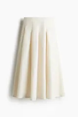 Pollera midi color crema, de tiro alto, con tablas y silueta evasé.