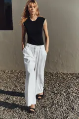 Camiseta negra de cuello redondo y sisa con detalle de fornitura con hilo metalizado a contraste en las mangas.