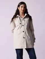 Gabardina impermeable color beige, marca Weatherproof, con abertura central con botones, bolsillos delanteros y capucha desmontable.