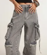 Pantalón baggy gris de jeans con bolsillos cargo laterales y tiritas ajustables.