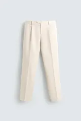 Pantalón de vestir color beige claro, corte regular fit, con pliegues frontales, bolsillos laterales y bolsillos traseros de vivo.