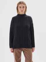 Buzo tejido color blanco, con cuello subido tipo polera, diseño oversized y largo con pequeños cortes laterales.