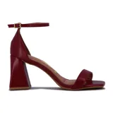 Sandalia de tacón alto color blanco, con una tira delgada sobre los dedos y pulsera con hebilla al tobillo.