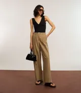 Pantalón wide leg color beige, de corte sastrero, con pliegues delanteros y cinturón.