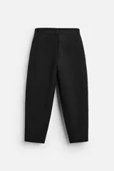 Pantalón negro de corte amplio tipo balloon fit, con cintura con pliegues frontales, bolsillos delanteros y traseros de plastrón. Cierre frontal con cremallera y botón.