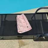 Short de baño negro con estampado de siluetas rojas, cintura elástica con cordón blanco y logo de la marca en la pierna.