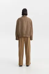 Chaqueta de lana y poliéster con diseño de pata de gallo en tonos marrones y verdes. Presenta cuello solapa, cierre frontal asimétrico con cremallera y botones, y puños con botón.