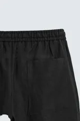 Pantalón de lino color marrón oscuro, de corte recto y relaxed fit. Tiene cintura elástica ajustable con cordón, bolsillos frontales y traseros de parche.