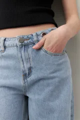 Pantalón de jean negro de corte ultra wide, tiro medio y detalles metálicos en la cintura.