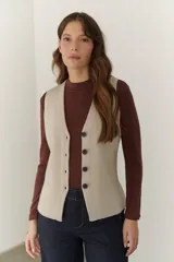 Chaleco gris de tejido de punto con cuello en V, cierre frontal con botones y bolsillos delanteros.
