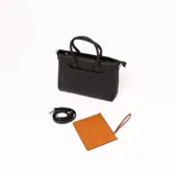 Cartera negra con doble asa corta y correa larga extraíble. Tiene bolsillo externo con cierre color marrón.