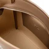 Bolso tote color beige, de cuero sintético, con doble asa de mano y correa bandolera desmontable y regulable. Tiene cierre superior, herrajes dorados y un bolsillo interno con cierre.