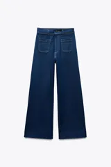 Pantalón de jean de tiro alto color negro con pierna ancha, bolsillos delanteros y traseros, y cierre frontal con cremallera y botón metálico.